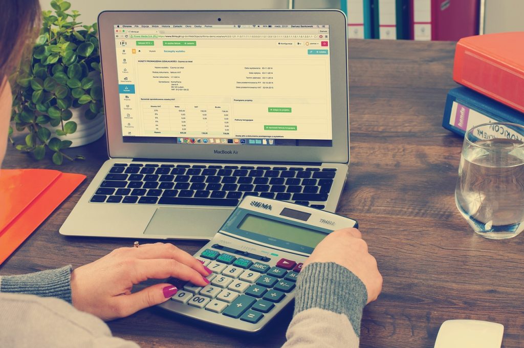 An image of a person and a laptop and calculator on a table